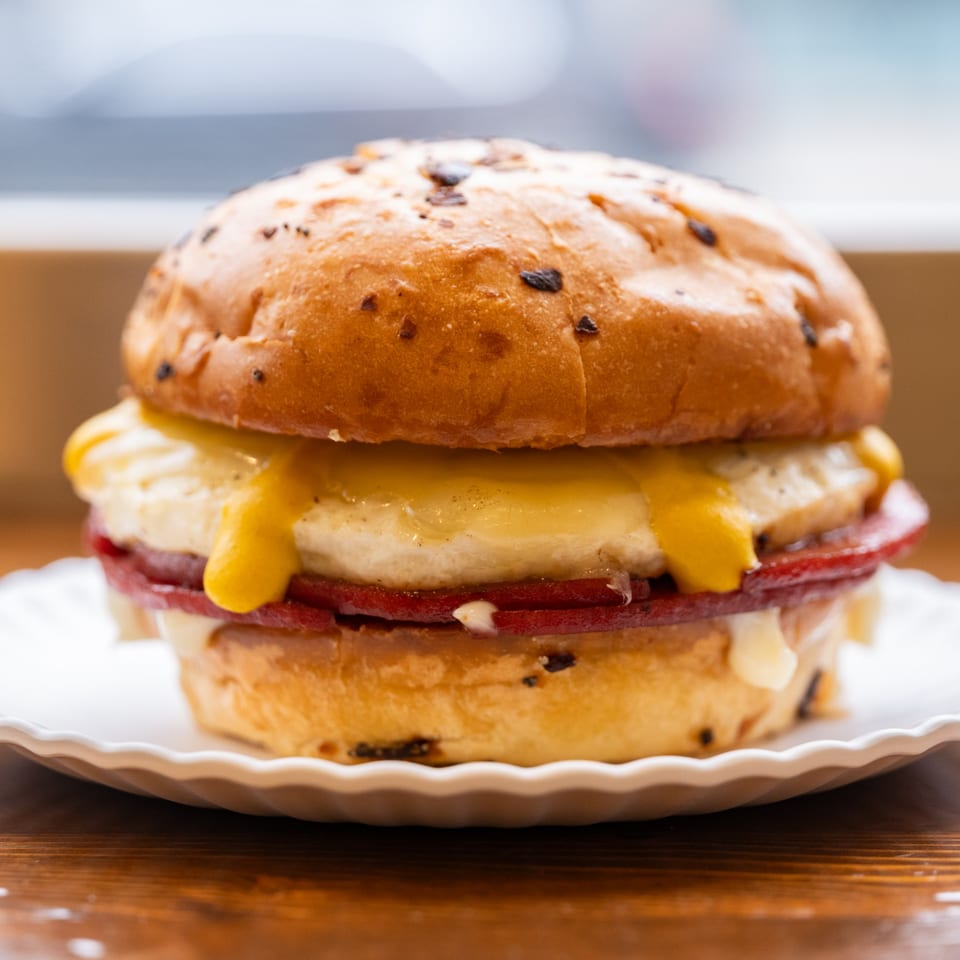 Close-up of an Iggy's Eggies sandwich with egg, cheese, and meat on a toasted bun.